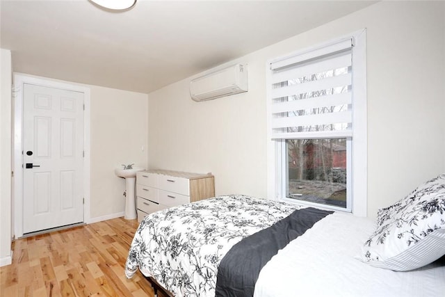 bedroom with light hardwood / wood-style floors and an AC wall unit