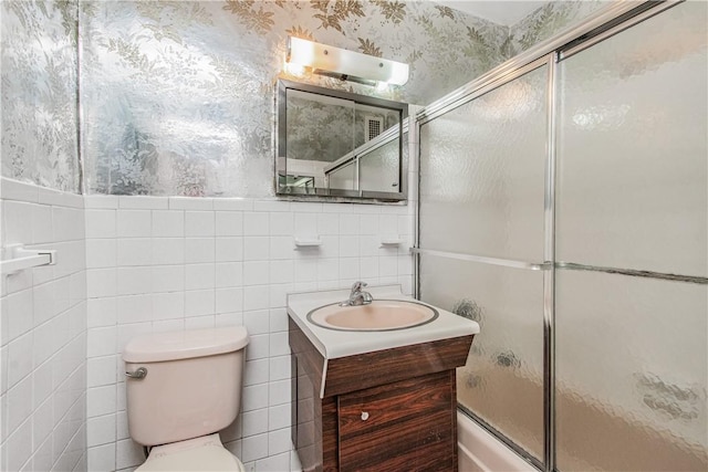 bathroom with vanity, toilet, and tile walls