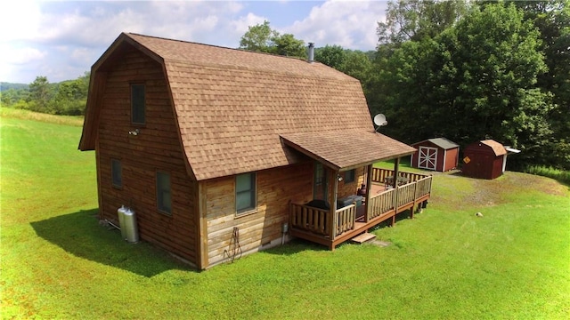 back of house featuring a storage unit, a deck, and a yard