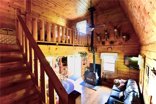 unfurnished living room featuring ceiling fan, lofted ceiling, wooden walls, wood ceiling, and hardwood / wood-style flooring