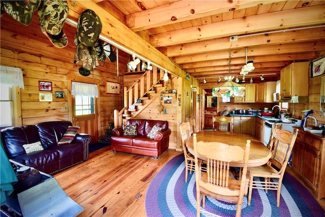 dining space featuring wood walls, wooden ceiling, sink, light hardwood / wood-style flooring, and beamed ceiling