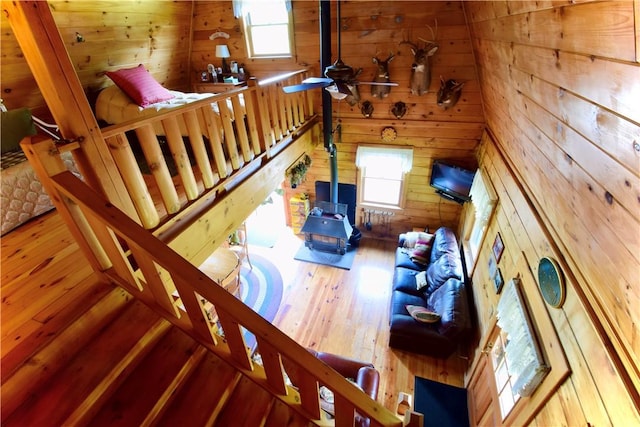 stairway with hardwood / wood-style flooring, plenty of natural light, wooden walls, and ceiling fan