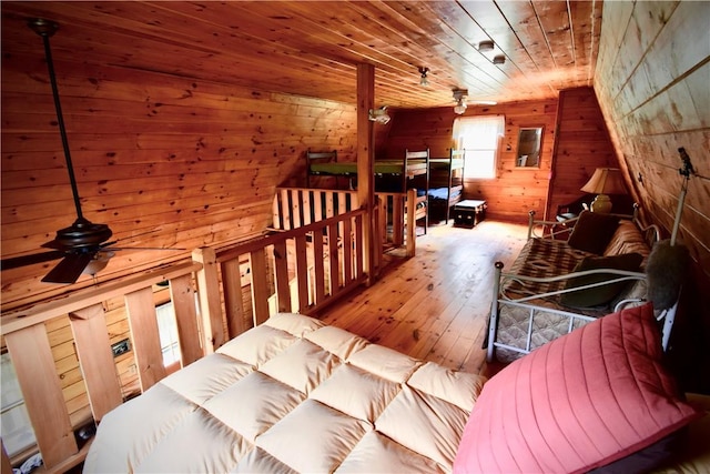 interior space featuring a wealth of natural light, ceiling fan, wood walls, and light wood-type flooring