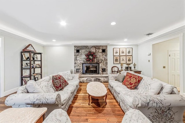 living room with a fireplace, ornamental molding, and light wood-type flooring