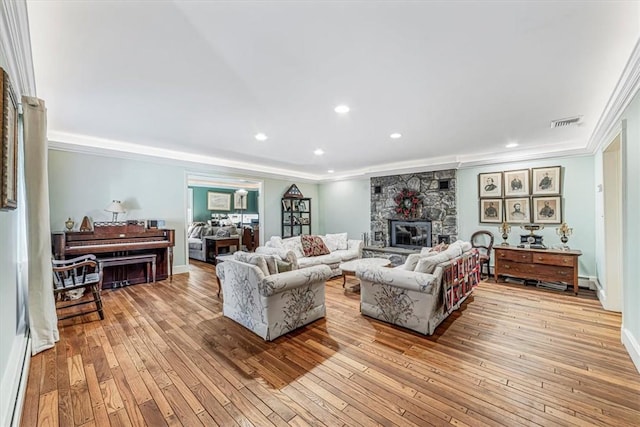 living room featuring crown molding, light wood-type flooring, and a fireplace