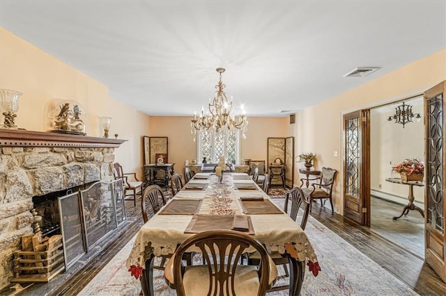 dining space with dark hardwood / wood-style floors, a stone fireplace, a wealth of natural light, and a chandelier