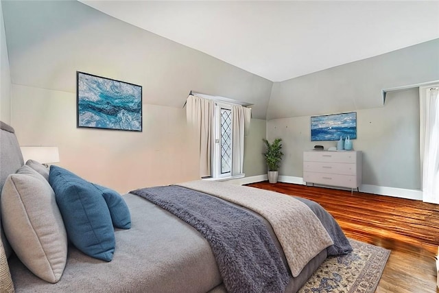 bedroom featuring hardwood / wood-style floors, lofted ceiling, and multiple windows