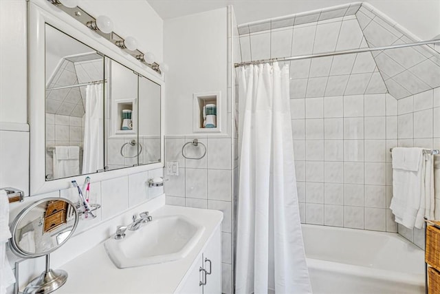 bathroom with vanity, shower / bathtub combination with curtain, and tile walls