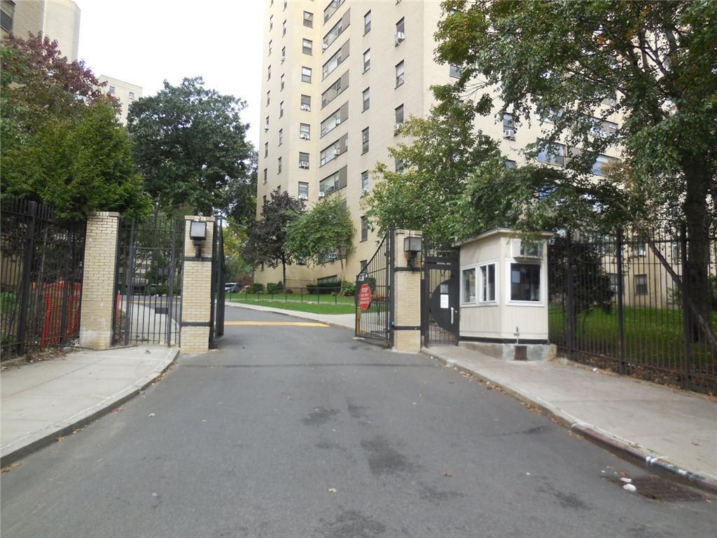 4 Fordham Hill Oval Unit 3D, Bronx, NY 10468 - view of asphalt road featuring a gate, curbs, sidewalks, a gated entry, and traffic signs