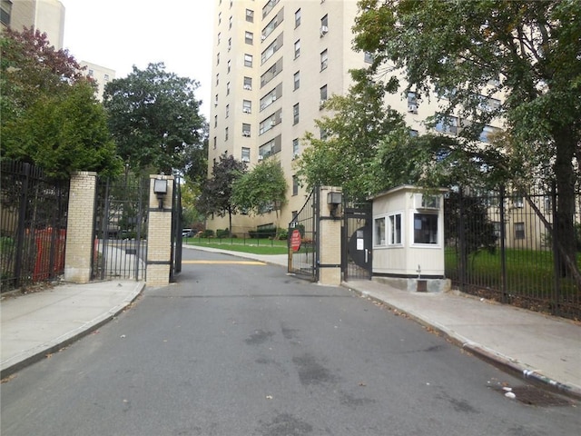 4 Fordham Hill Oval Unit 3D, Bronx, NY 10468 - view of asphalt road featuring a gate, curbs, sidewalks, a gated entry, and traffic signs