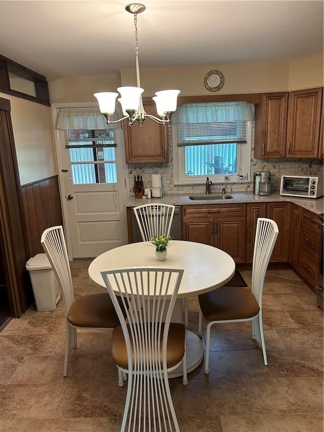 kitchen featuring pendant lighting, plenty of natural light, light stone counters, and sink