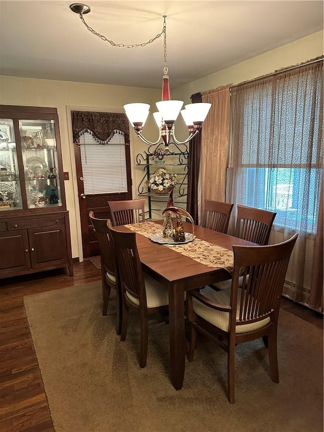 dining area with dark hardwood / wood-style floors and a notable chandelier