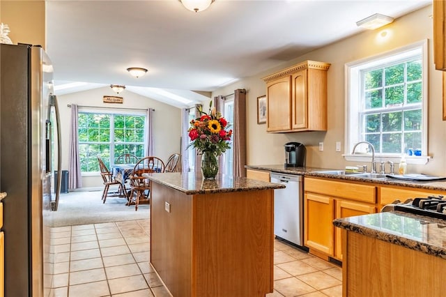 kitchen featuring dark stone counters, stainless steel appliances, sink, a center island, and lofted ceiling