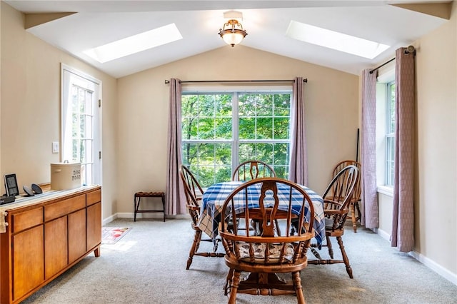 dining room with light carpet, plenty of natural light, and vaulted ceiling with skylight