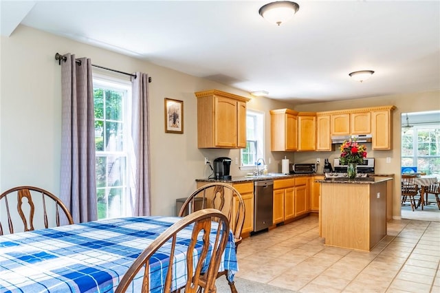 kitchen featuring dark stone countertops, a center island, light brown cabinetry, and appliances with stainless steel finishes