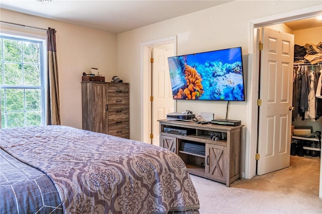 bedroom featuring light carpet, a spacious closet, and a closet