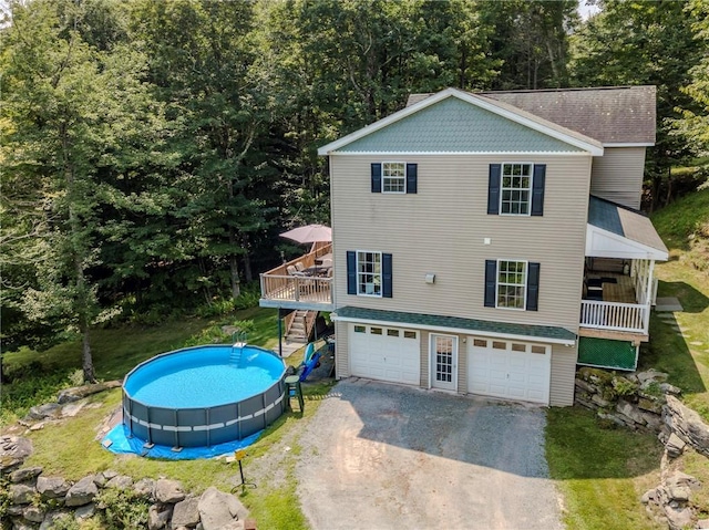 rear view of property featuring a pool side deck and a garage