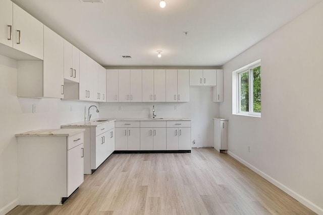 23 Northbrook Rd Unit 202, Spring Valley, NY 10977 - kitchen featuring light wood finished floors, baseboards, a sink, and white cabinets