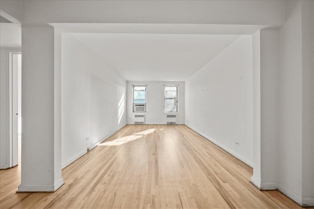 empty room featuring radiator heating unit and light wood-type flooring