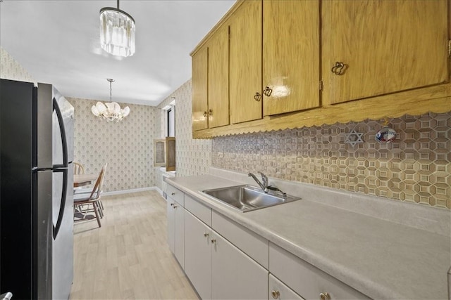 kitchen featuring a chandelier, stainless steel refrigerator, hanging light fixtures, and sink