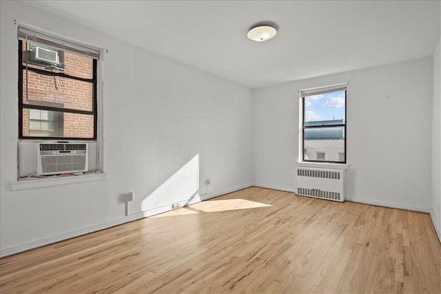 empty room featuring radiator heating unit, cooling unit, and light hardwood / wood-style floors