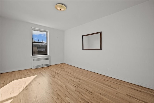 spare room with radiator heating unit and light wood-type flooring