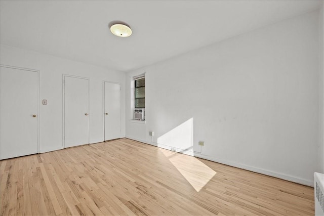 unfurnished bedroom featuring light hardwood / wood-style floors and cooling unit