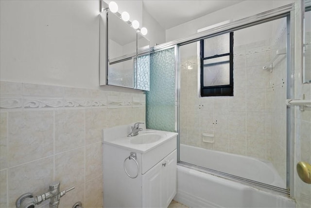 bathroom featuring vanity, tile walls, and combined bath / shower with glass door