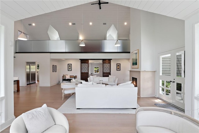 living room featuring elevator, wood-type flooring, high vaulted ceiling, and french doors