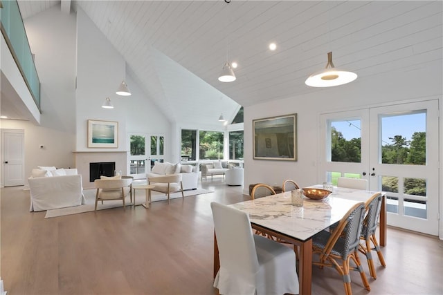 dining space featuring beam ceiling, french doors, high vaulted ceiling, and hardwood / wood-style flooring