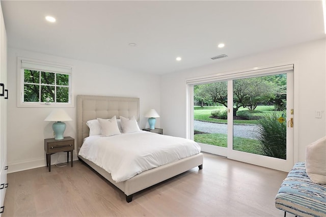 bedroom featuring wood-type flooring, access to outside, and multiple windows