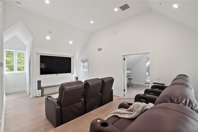 cinema with light hardwood / wood-style flooring and high vaulted ceiling