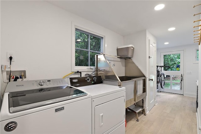 clothes washing area featuring light hardwood / wood-style floors, a healthy amount of sunlight, and separate washer and dryer