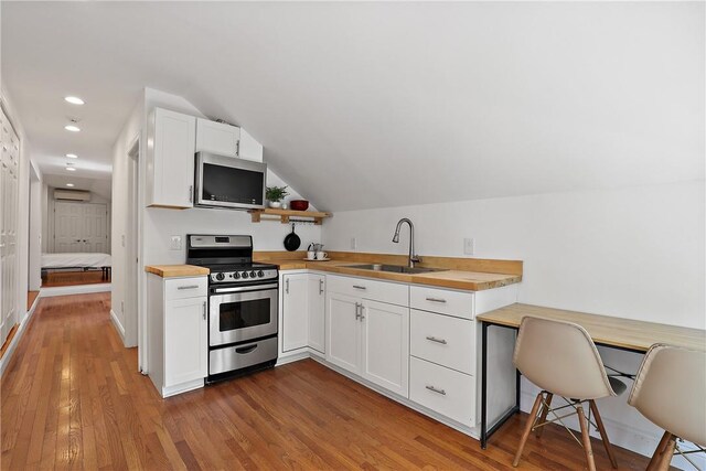 kitchen featuring wood counters, stainless steel appliances, sink, light hardwood / wood-style flooring, and white cabinetry