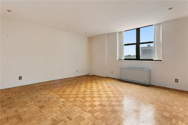 spare room with radiator heating unit and light parquet floors