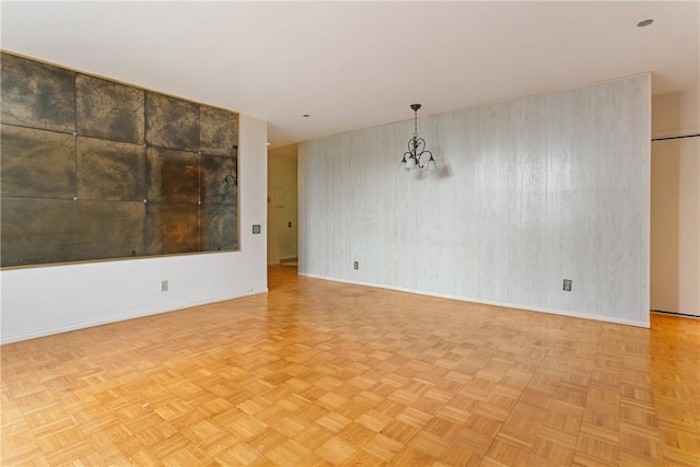 empty room with a chandelier and light parquet flooring