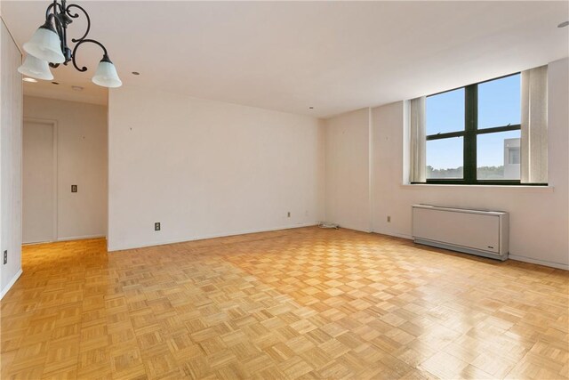 unfurnished room with radiator heating unit and light parquet floors