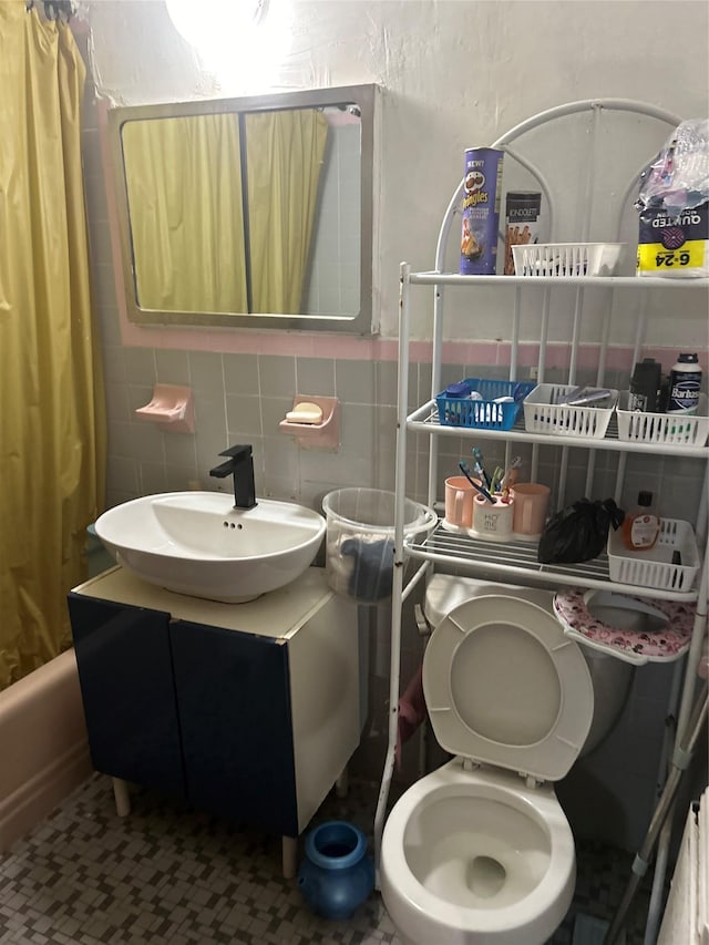 full bathroom featuring tasteful backsplash, tile walls, vanity, shower / tub combo, and toilet