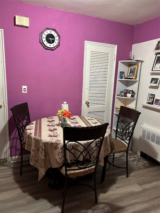 dining area with wood-type flooring and radiator heating unit