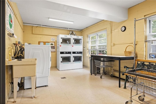 kitchen featuring oven, a healthy amount of sunlight, stacked washer / dryer, and washing machine and clothes dryer