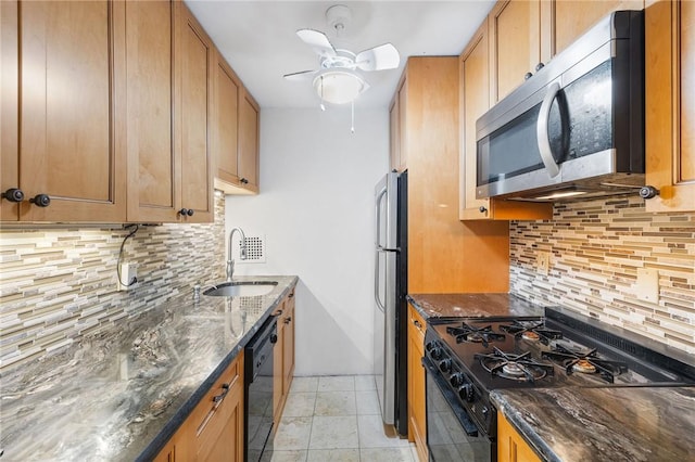 kitchen featuring ceiling fan, sink, dark stone counters, decorative backsplash, and black appliances