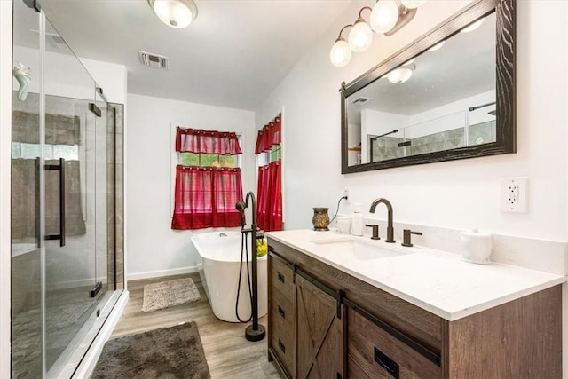 bathroom with hardwood / wood-style floors, vanity, and shower with separate bathtub