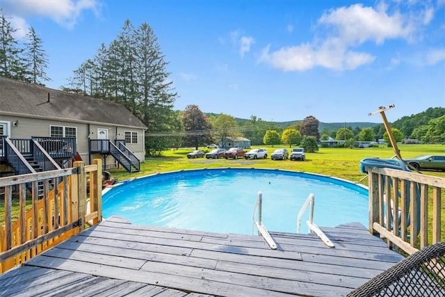 view of swimming pool featuring a lawn and a wooden deck