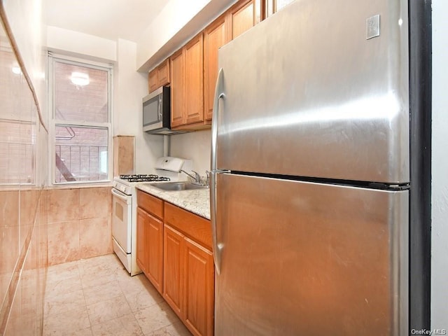 kitchen with light stone countertops, sink, and appliances with stainless steel finishes