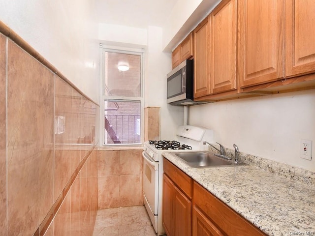 kitchen featuring light stone countertops, white range with gas cooktop, and sink