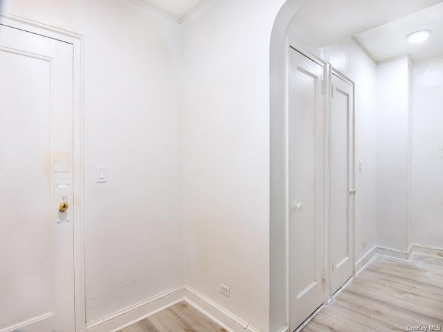 corridor with light hardwood / wood-style floors and crown molding