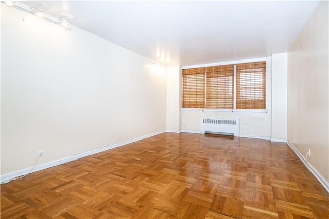 spare room featuring parquet floors and radiator