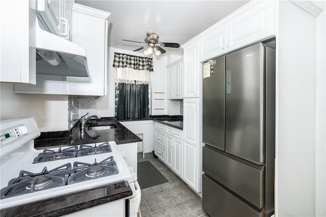 kitchen featuring ceiling fan, white range with gas cooktop, sink, white cabinets, and stainless steel refrigerator