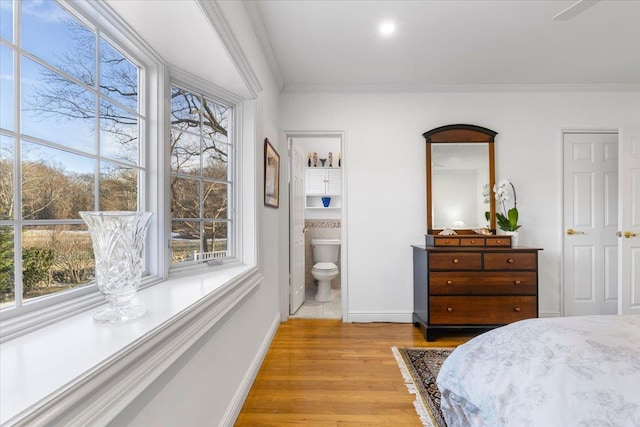 bedroom featuring ornamental molding, connected bathroom, light wood-style flooring, and baseboards