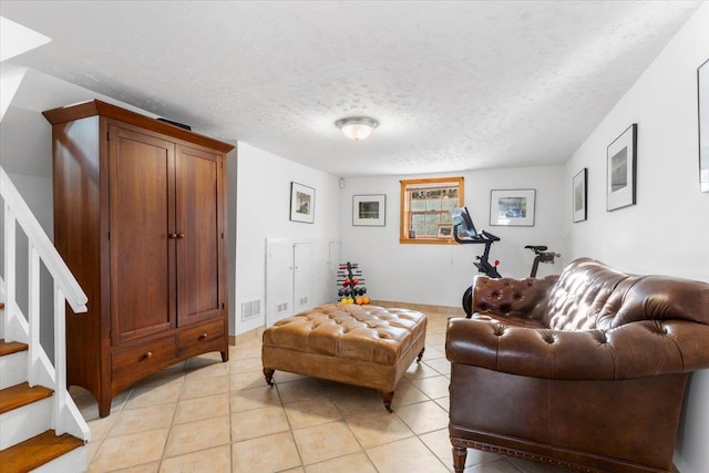 living area featuring stairs, a textured ceiling, and light tile patterned flooring